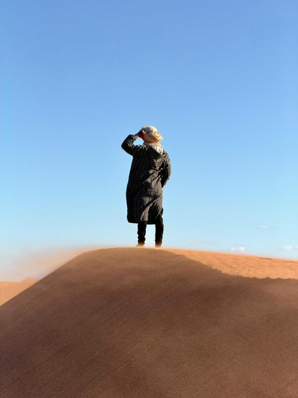 Majid au cœur des dunes de l’Erg Chgaga, contemplant l’horizon du désert marocain.